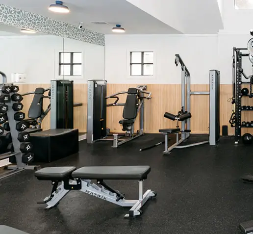 Apartment fitness center with machines, benches, and weights.